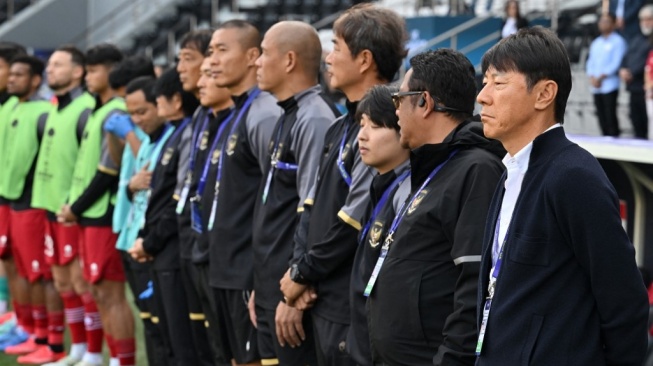 Pelatih Timnas Indonesia asal Korea Selatan Shin Tae-yong (kanan) berdiri bersama anggota timnya sebelum dimulainya pertandingan sepak bola Piala Asia AFC Qatar 2023 antara Australia dan Indonesia di Stadion Jassim bin Hamad di Doha pada 28 Januari 2024.HECTOR RETAMAL / AFP