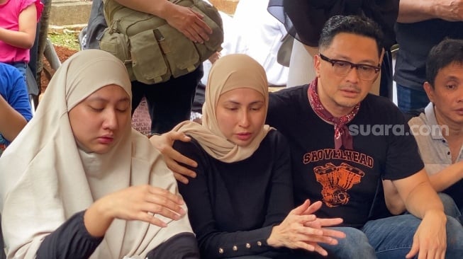 Ferry Maryadi dan Deswita Maharani berdoa di atas makaman sang ayah, Zainul Affendy di TPU Menteng Pulo, Jakarta Pusat, Sabtu (18/5/2024). [Adiyoga Priyambodo/Suara.com]