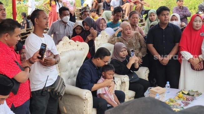 Eks Gubernur DKI Jakarta, Anies Baswedan mendekap anak kecil saat mengunjungi Kampung Marlina, Muara Baru, Jakarta Utara, pada Minggu (19/5/2024). (Suara.com/Fakhri)