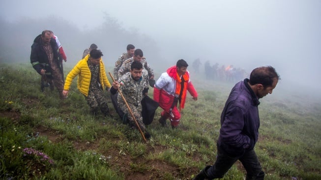 Tim penyelamat mengevakuasi jenazah di lokasi jatuhnya helikopter yang mengangkut Presiden Iran di daerah pegunungan Varzaghan di barat laut Iran, Senin (20/5/2024). [Azin HAGHIGHI / MOJ News Agency / AFP]