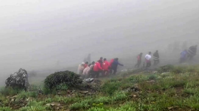 Gambar yang diambil dari cuplikan video ini menunjukkan tim penyelamat menemukan jenazah di lokasi jatuhnya helikopter Presiden Ebrahim Raisi di daerah pegunungan yang diselimuti kabut di barat laut Iran, Senin (20/5/2024). [Palang Merah Iran / AFP]