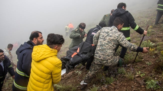 Tim penyelamat mengevakuasi jenazah di lokasi jatuhnya helikopter yang mengangkut Presiden Iran di daerah pegunungan Varzaghan di barat laut Iran, Senin (20/5/2024). [Azin HAGHIGHI / MOJ News Agency / AFP]