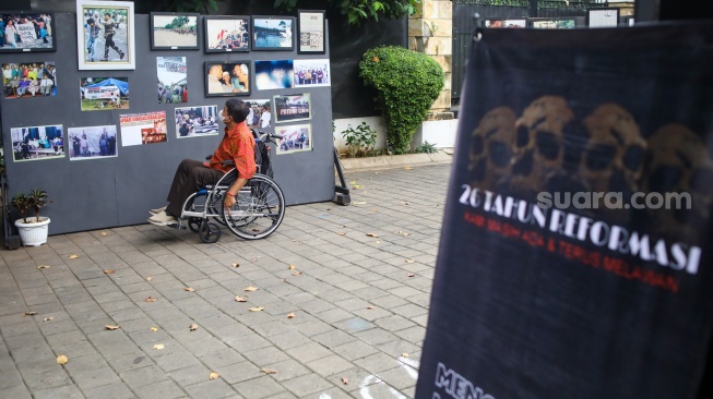 Aktivis hak asasi manusia (HAM) melihat pameran foto Peringatan 26 Tahun Reformasi di kawasan Menteng, Jakarta Pusat, Selasa (21/5/2024). [Suara.com/Alfian Winanto]