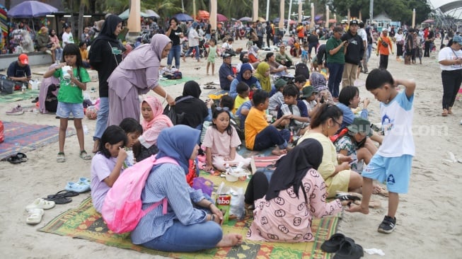 Pengunjung berwisata di Pantai Lagoon, Ancol Taman Impian, Jakarta, Minggu (26/5/2024). [Suara.com/Alfian Winanto]