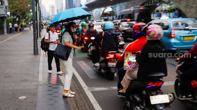 Pekerja melintas di kawasan Perkantoran Sudirman, Jakarta, Selasa (28/5/2024). [Suara.com/Alfian Winanto]