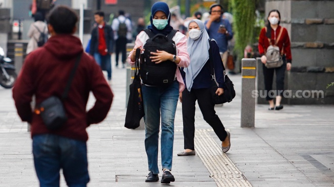 Pekerja melintas di kawasan Perkantoran Sudirman, Jakarta, Selasa (28/5/2024). [Suara.com/Alfian Winanto]