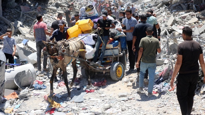 Warga Palestina membawa beberapa barang yang diselamatkan ketika mereka menuju kamp pengungsi Jabalia di Jalur Gaza utara, Jumat (30/5/2024). [Omar AL-QATTAA / AFP]