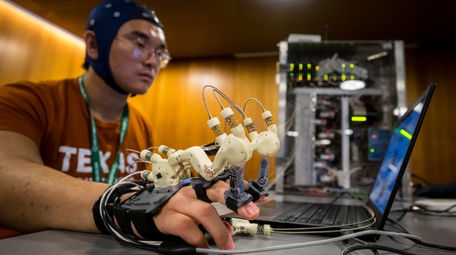 Seorang mahasiswa Texas Robotics menunjukkan antarmuka otak-komputer AI yang memungkinkan dia mengendalikan tangannya dengan pikirannya, selama konferensi pers di International Telecommunication Union (ITU) AI for Good Global Summit di Jenewa, Swiss, Kamis (30/5/2024). [Fabrice COFFRINI / AFP]
