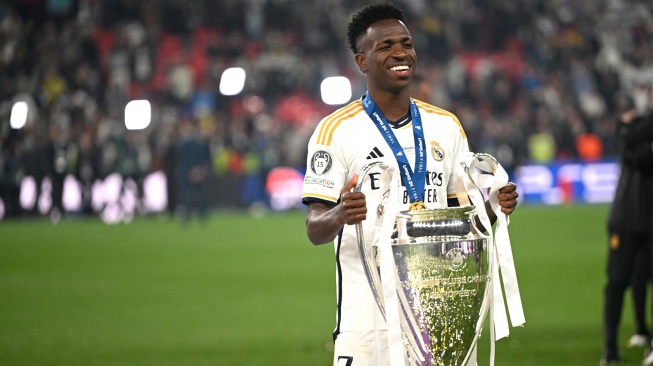 Penyerang Real Madrid Vinicius Junior berpose dengan trofi untuk merayakan kemenangan di akhir pertandingan sepak bola final Liga Champions 2023/2024 antara Real Madrid melawan Borussia Dortmund di Stadion Wembley, London, Inggris, Sabtu (1/6/2024). [INA FASSBENDER / AFP]