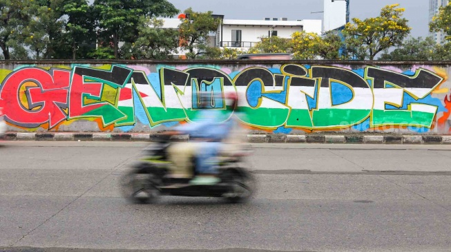 Pengendara melewati mural yang menggambarkan dukungan untuk warga Palestina di tembok pinggir tol lingkar luar Jakarta, Tanjung Barat, Jakarta Selatan, Senin (3/6/2024). [Suara.com/Alfian Winanto]