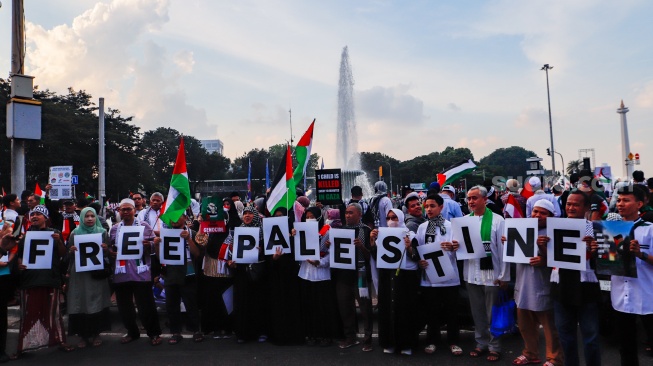 Massa mengangkat poster saat Aksi Bela Palestina di Kawasan Patung Kuda, Jakarta, Minggu (9/6/2024). [Suara.com/Alfian Winanto]