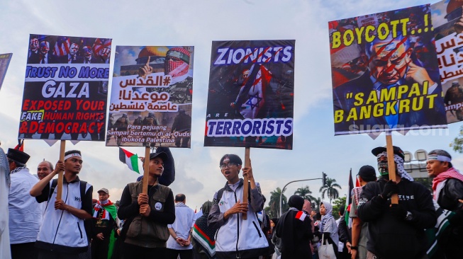 Massa mengangkat poster saat Aksi Bela Palestina di Kawasan Patung Kuda, Jakarta, Minggu (9/6/2024). [Suara.com/Alfian Winanto]