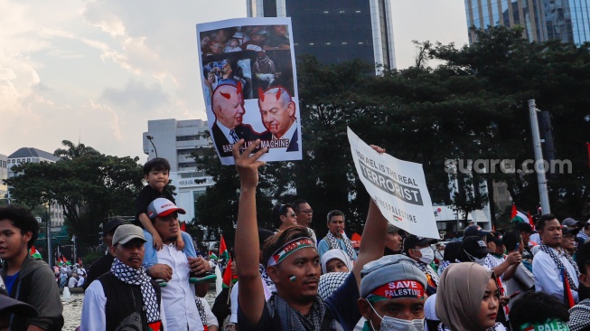 Massa mengangkat poster saat Aksi Bela Palestina di Kawasan Patung Kuda, Jakarta, Minggu (9/6/2024). [Suara.com/Alfian Winanto]