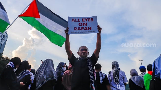 Massa mengangkat poster saat Aksi Bela Palestina di Kawasan Patung Kuda, Jakarta, Minggu (9/6/2024). [Suara.com/Alfian Winanto]