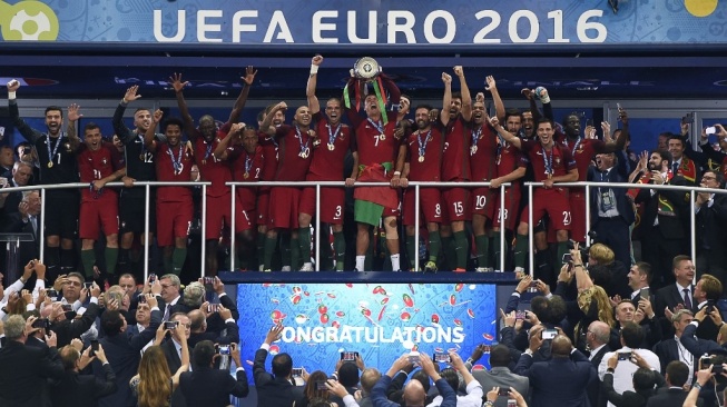 Pemain depan Portugal Cristiano Ronaldo (tengah) mengangkat trofi saat ia merayakan bersama rekan satu timnya setelah Portugal mengalahkan Prancis pada pertandingan sepak bola final Euro 2016 di Stade de France di Saint-Denis, utara Paris, pada 10 Juli 2016.PHILIPPE DESMAZES / AFP