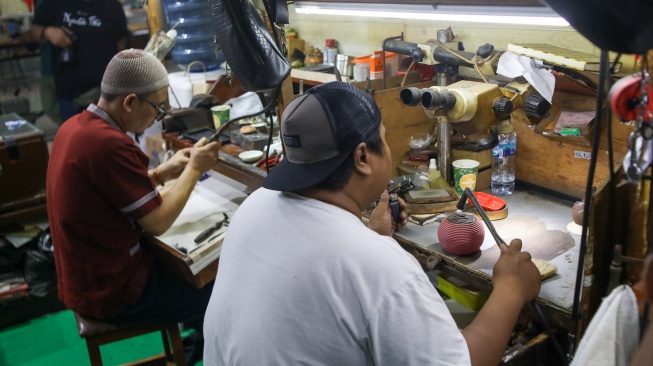 Perajin menyelesaikan pembuatan cincin di Metro Pasar Baru, Jakarta Pusat, Jumat (14/6/2024). [Suara.com/Alfian Winanto]