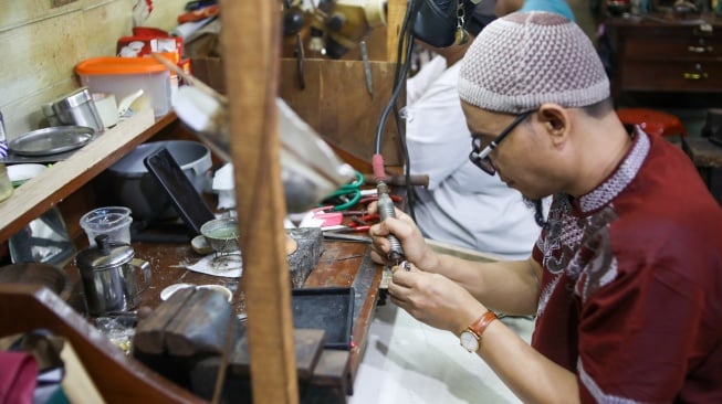 Perajin menyelesaikan pembuatan cincin di Metro Pasar Baru, Jakarta Pusat, Jumat (14/6/2024). [Suara.com/Alfian Winanto]