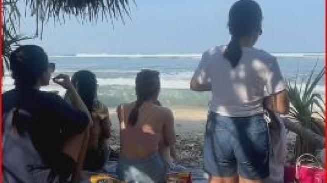 Santai di Pantai, Wisatawan Ini Diduga Melamun Saat Ombak Datang