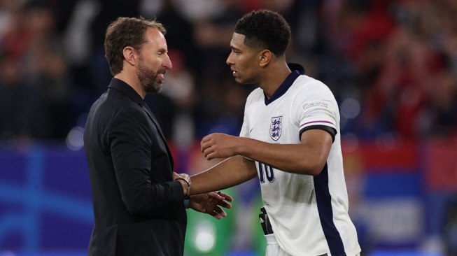 Pelatih kepala Inggris Gareth Southgate merayakan bersama gelandang Inggris Jude Bellingham di akhir pertandingan sepak bola Grup C UEFA Euro 2024 antara Serbia dan Inggris di Arena AufSchalke di Gelsenkirchen pada 16 Juni 2024.Adrian DENNIS / AFP