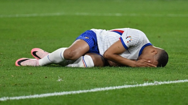 Penyerang timnas Prancis, Kylian Mbappe terbaring di lapangan setelah cedera patah hidung selama pertandingan Grup D Euro 2024 antara Austria vs Prancis di Duesseldorf Arena di Duesseldorf pada 17 Juni 2024.OZAN KOSE / AFP.