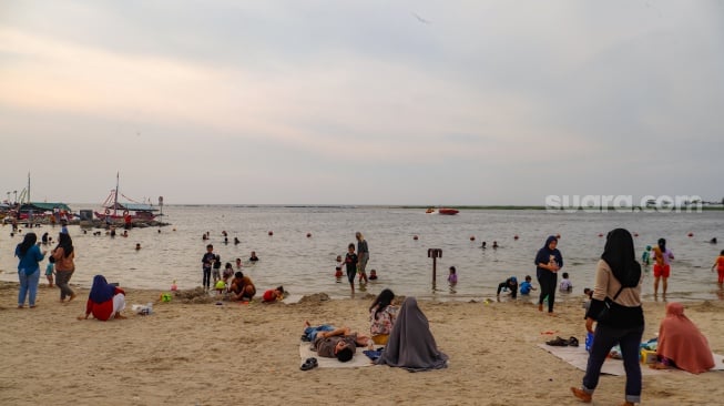 Pengunjung berwisata di Pantai Lagoon, Ancol Taman Impian, Jakarta, Selasa (18/6/2024). [Suara.com/Alfian Winanto]