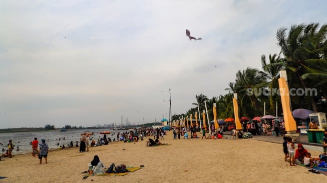 Pengunjung berwisata di Pantai Lagoon, Ancol Taman Impian, Jakarta, Selasa (18/6/2024). [Suara.com/Alfian Winanto]