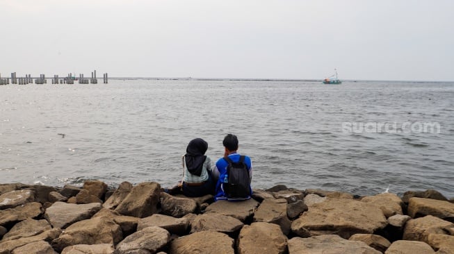 Pengunjung berwisata di Pantai Lagoon, Ancol Taman Impian, Jakarta, Selasa (18/6/2024). [Suara.com/Alfian Winanto]