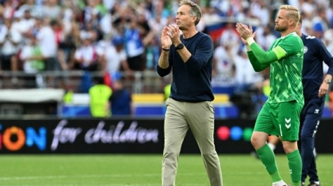 Pelatih kepala Denmark Kasper Hjulmand dan kiper Denmark #01 Kasper Schmeichel bertepuk tangan kepada para penggemar mereka setelah pertandingan sepak bola Grup C UEFA Euro 2024 antara Slovenia dan Denmark di Stuttgart Arena di Stuttgart pada 16 Juni 2024. THOMAS KIENZLE / AFP