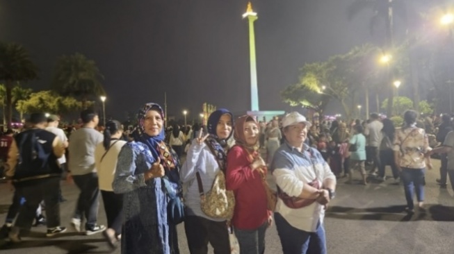 Warga dari Penggilingan berfoto dengan latar Monas saat Malam Jaya Raya, Sabtu (22/6/2024) (Dokumentasi: Suara.com)