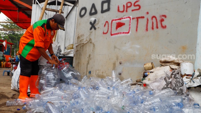 Petugas Unit Penanganan Sampah (UPS) Badan Air Dinas Lingkungan Hidup DKI Jakarta Kecamatan Jatinegara memilih galon bekas untuk dibuat ondel-ondel mini dari galon air minum bekas di Jakarta, Selasa (25/6/2024). [Suara.con/Alfian Winanto]