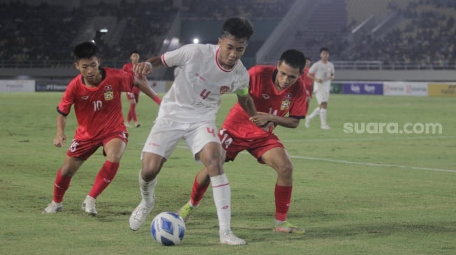 Kapten Timnas Indonesia U-16, I Putu Panji Apriawan diadang dua pemain Laos dalam pertandingan ketiga Grup A Piala AFF U-16 2024 di Stadion Manahan, Solo, Kamis (27/6/2024). [Suara.com / Ronald Seger Prabowo]