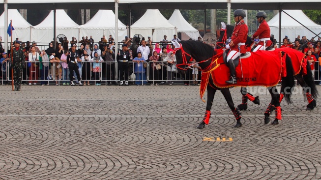 Warga menonton pertunjukan defile pasukan berkuda saat upacara peringatan HUT ke-78 Bhayangkara di Lapangan Silang Monas, Jakarta, Senin (1/7/2024). [Suara.com/Alfian Winanto]