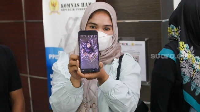 Ibunda Afif Maulana, Anggun Andriani (tengah)  menunjukkan foto anaknya saat usai melakukan audiensi di kantor Komnas HAM, Jakarta, Senin (1/7/2024). [Suara.com/Alfian Winanto]