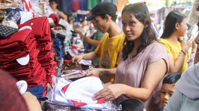 Warga memilih seragam sekolah di Toko Seragam di Pasar Jatinegara, Jakarta, Selasa (2/7/2024). [Suara.com/Alfian Winanto]