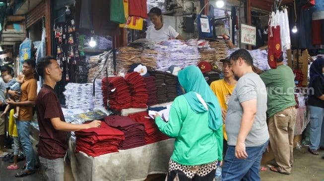 Warga memilih seragam sekolah di Toko Seragam di Pasar Jatinegara, Jakarta, Selasa (2/7/2024). [Suara.com/Alfian Winanto]