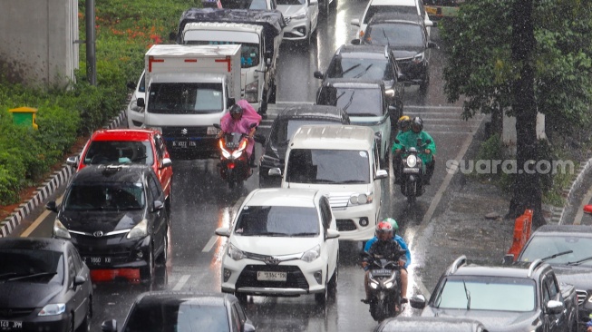 Pengendara motor melintas saat hujan lebat di Jalan Gatot Subroto, Jakarta, Selasa (2/7/2023). [Suara.com/Alfian Winanto]