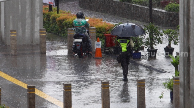 Warga berjalan saat menggunakan payung saat hujan lebat di Jalan Gatot Subroto, Jakarta, Selasa (2/7/2023). [Suara.com/Alfian Winanto]