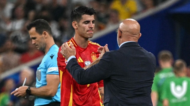 Penyerang timnas Spanyol, Alvaro Morata meninggalkan lapangan di samping pelatih kepala Luis de la Fuente setelah diganti selama pertandingan semifinal UEFA Euro 2024 antara Spanyol vs Prancis di Munich Football Arena di Munich pada 9 Juli 2024.JAVIER SORIANO / AFP.