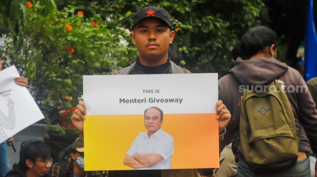 Massa membawa poster saat menggelar aksi di depan gedung Kementerian Komunikasi dan Informatika (Kemenkominfo) di Jakarta, Rabu (10/7/2024). [Suara.com/Alfian Winanto]