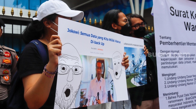 Massa membawa poster saat menggelar aksi di depan gedung Kementerian Komunikasi dan Informatika (Kemenkominfo) di Jakarta, Rabu (10/7/2024). [Suara.com/Alfian Winanto]