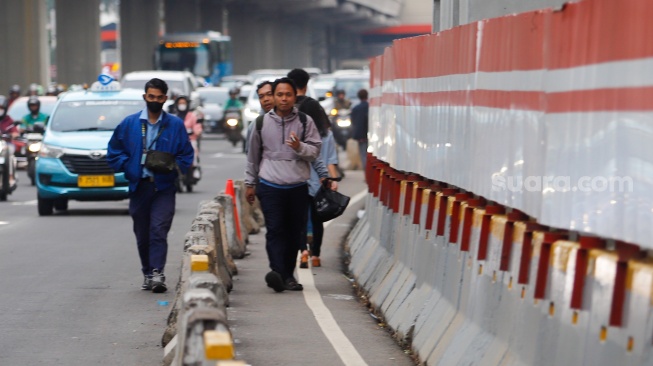 Sejumlah pejalan kaki melintas disamping proyek galian di Jl Rasuna Said, Jakarta, Rabu (10/7/2024). [Suara.com/Alfian Winanto]
