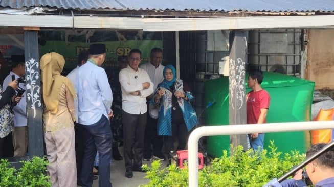 Penjabat (Pj) Gubernur DKI Jakarta Heru Budi Hartono meninjau instalasi biogas di peternakan sapi yang terletak di Kelurahan Cikoko, Pancoran, Jakarta Selatan, pada Jumat (12/7/2024). [Suara.com/Fakhri]