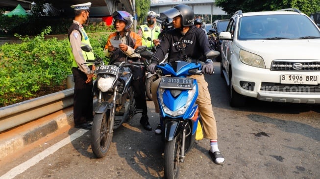 Sejumlah petugas kepolisian memberikan himbauan kepada pengendara yang melanggar peraturan saat Operasi Patuh Jaya 2024 di Jalan Letjen S Parman, Jakarta, Senin (15/07/2024). [Suara.com/Alfian Winanto]