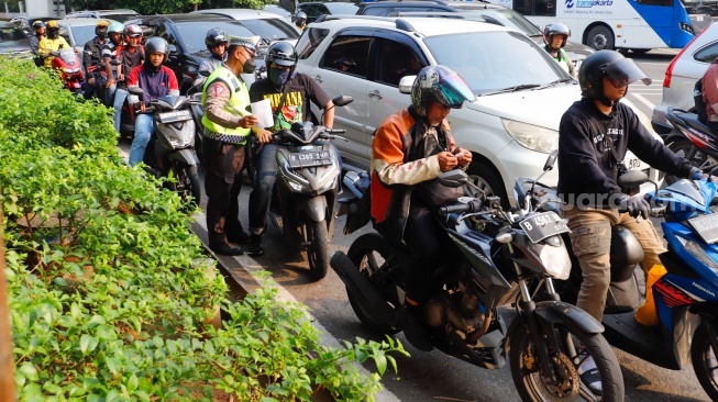 Sejumlah petugas kepolisian memberikan himbauan kepada pengendara yang melanggar peraturan saat Operasi Patuh Jaya 2024 di Jalan Letjen S Parman, Jakarta, Senin (15/07/2024). [Suara.com/Alfian Winanto]