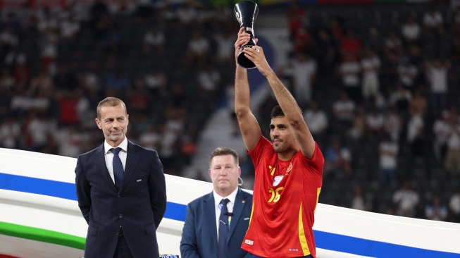 Gelandang Spanyol Rodri menerima trofi pemain terbaik setelah memenangkan pertandingan sepak bola Final Euro 2024 antara Spanyol dan Inggris di Olympiastadion, Berlin, Jerman, Minggu (14/7/2024). [Adrian DENNIS / AFP]