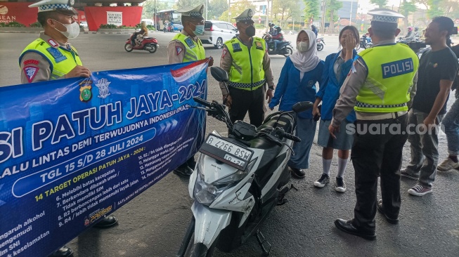 Sejumlah petugas kepolisian memberikan himbauan kepada pengendara yang melanggar peraturan saat Operasi Patuh Jaya 2024 di Jalan Letjen S Parman, Jakarta, Senin (15/07/2024). [Suara.com/Alfian Winanto]