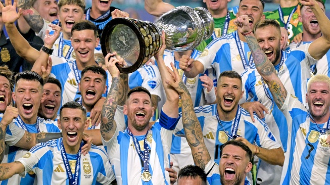 Penyerang Argentina Lionel Messi berselebrasi mengangkat trofi bersama para pemain Timnas Argentin usai pertandingan sepak bola final Copa America 2024 antara Argentina dan Kolombia di Stadion Hard Rock, di Miami, Florida, Minggu (14/7/2024). [CHARLY TRIBALLEAU / AFP]