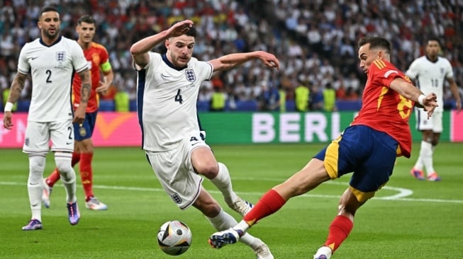 Gelandang timnas Inggris, Declan Rice (tengah) berebut bola dengan gelandang Spanyol, Fabian Ruiz selama pertandingan final UEFA Euro 2024 antara Spanyol vs Inggris di Olympiastadion di Berlin pada Senin (15/7/2024) dini hari WIB.JAVIER SORIANO / AFP.