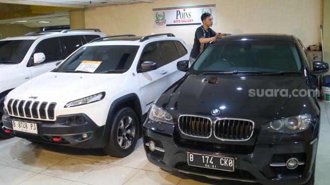 Penjual membersihkan mobil bekas yang dijual di bursa mobil bekas Blok M, Jakarta, Jumat (19/7/2024). [Suara.com/Alfian Winanto]