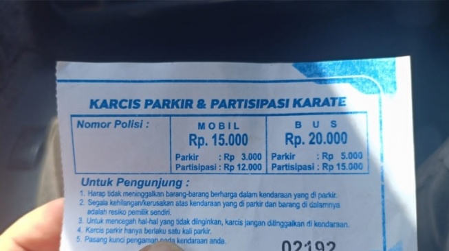 Karcis parkir dengan tarif tambahan partisipasi, saat ditunjukkan pengunjung yang memarkir kendaraan di halaman parkir GOR Kanjuruhan Sport, Kabupaten Malang, Sabtu (20/7/2024). [TIMES Indonesia]